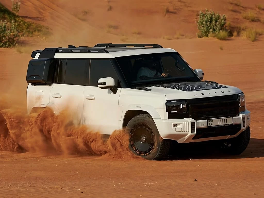 A white Jetour T2 driving on desert sand in Dubai